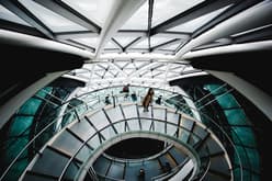 An internal view of the Gherkin looking down onto stairs with people standing and walking on them