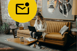 A woman sitting on a mustard sofa with a laptop on her lap in a cool looking office. At the top left of the image is a large yellow circle containing a black envelope icon with a black circle on the top right corner indicating there is unopened email