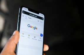 Google search on a mobile phone being held in a hand