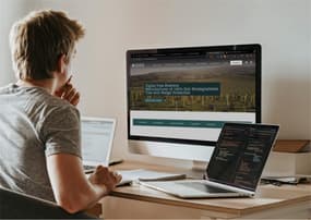 Developer working on a website with a large computer and two laptops