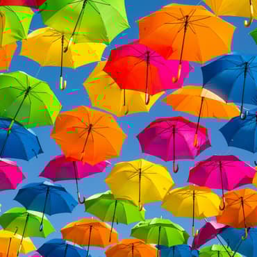 A blue sky with lots of different colour umbrells in lines connected by string, with the photo taken from below so you can see up inside the umbrellas