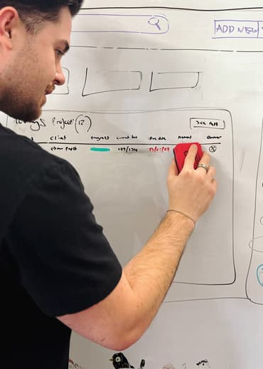 Person updating a wireframe on a whiteboard