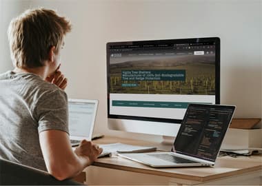 Developer working on a website with a large computer and two laptops