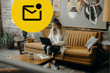 A woman sitting on a mustard sofa with a laptop on her lap in a cool looking office. At the top left of the image is a large yellow circle containing a black envelope icon with a black circle on the top right corner indicating there is unopened email