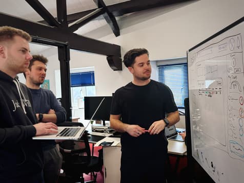 Three men having a discussion around a wireframe on a whiteboard