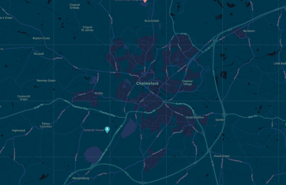 A dark blue map of Chelmsford, a city in Essex, England, showing a network of roads and surrounding areas. The map features light dark tones, with the city centre marked clearly. Key locations include Chelmer Village, Writtle, and Great Baddow, represented by small text labels. Green patches indicate parks or fields, while major roads are highlighted in orange. Hylands House is marked with a blue icon, indicating a point of interest. The overall layout provides a clear view