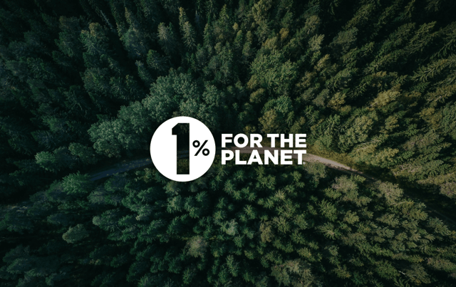 An aerial view of a dense forest, featuring a variety of green trees and foliage. In the centre, there is a large white circle containing the text "1%" in bold black font, positioned above the words "FOR THE PLANET" in a smaller black font. A winding dirt path can be seen cutting through the forest, adding a sense of depth and perspective to the image. The overall tone conveys a message of environmental awareness and conservation.