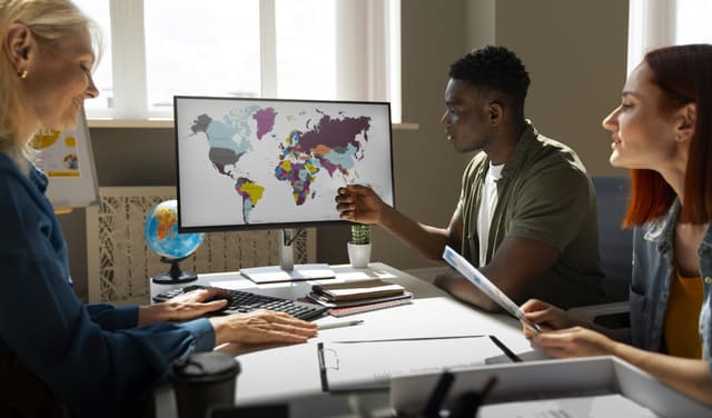 3 people around a screen discussing with a map discussing translation languages