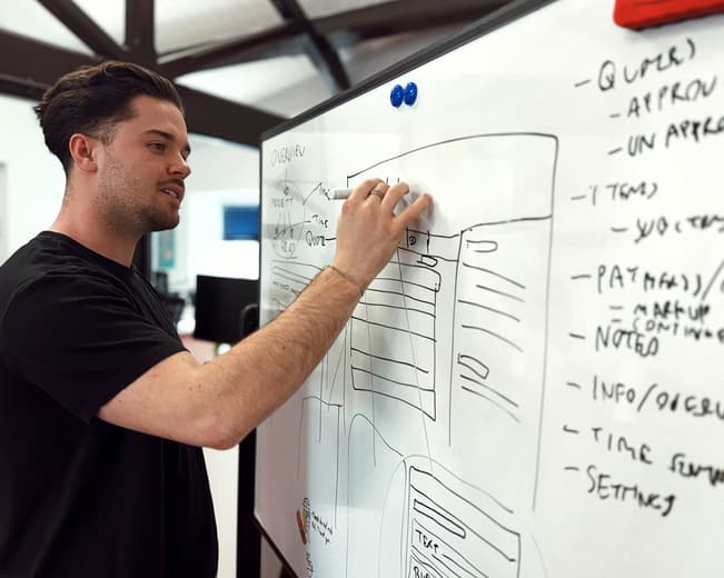 Man updating a wireframe on a whiteboard