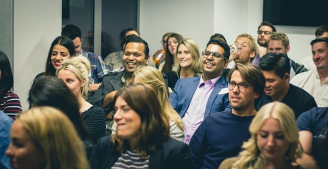 Large audience at an event and most are smiling or laughing